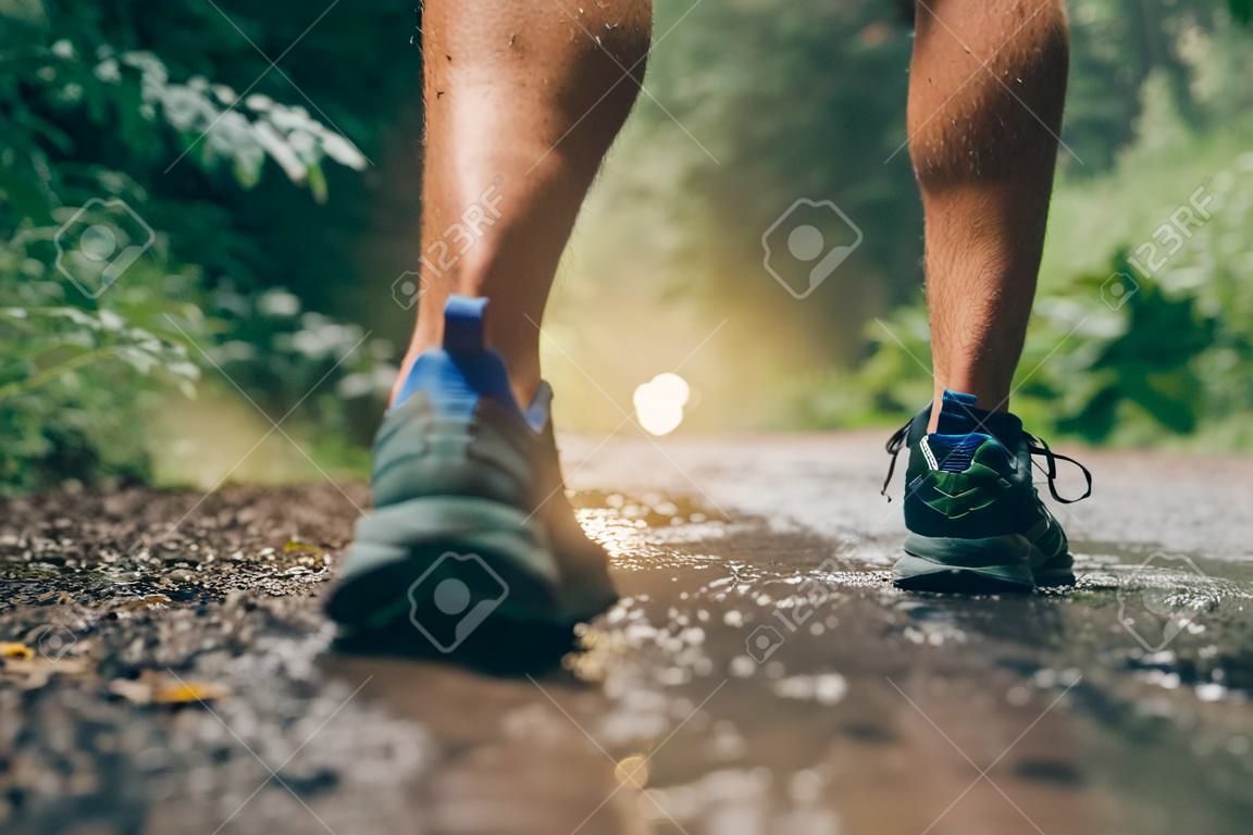 Boves musculosos de treinamento de corredores masculinos aptos para corrida de trilha de floresta de cross country na chuva em uma trilha de natureza.