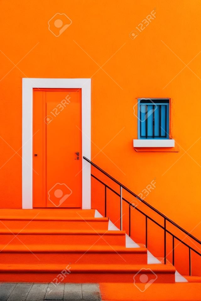 Colorful door and stairs on the orange wall of a house.