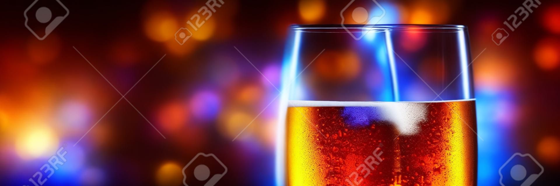 full glass of beer on blurred lights background panorama