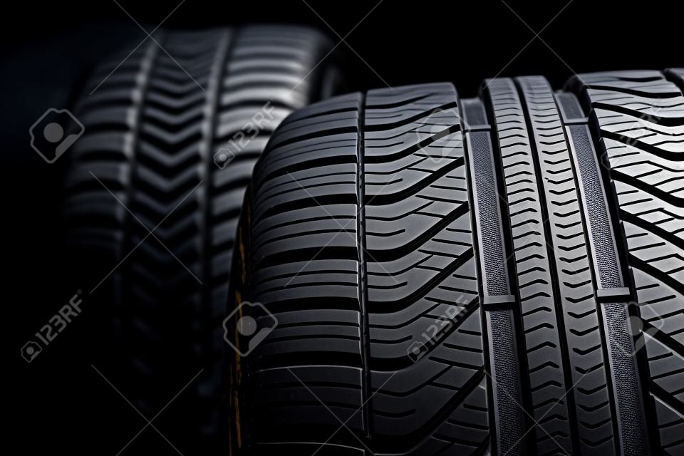 Row of car tires with a profile close-up on a black background.