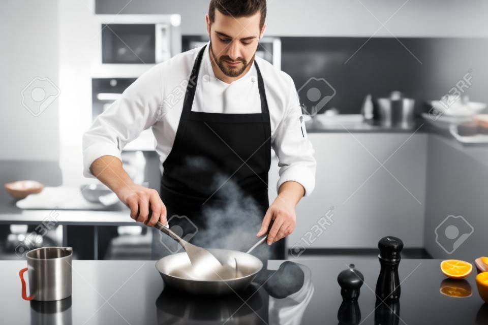 Chef preparazione di piatti in una padella. Cucinando. immagine