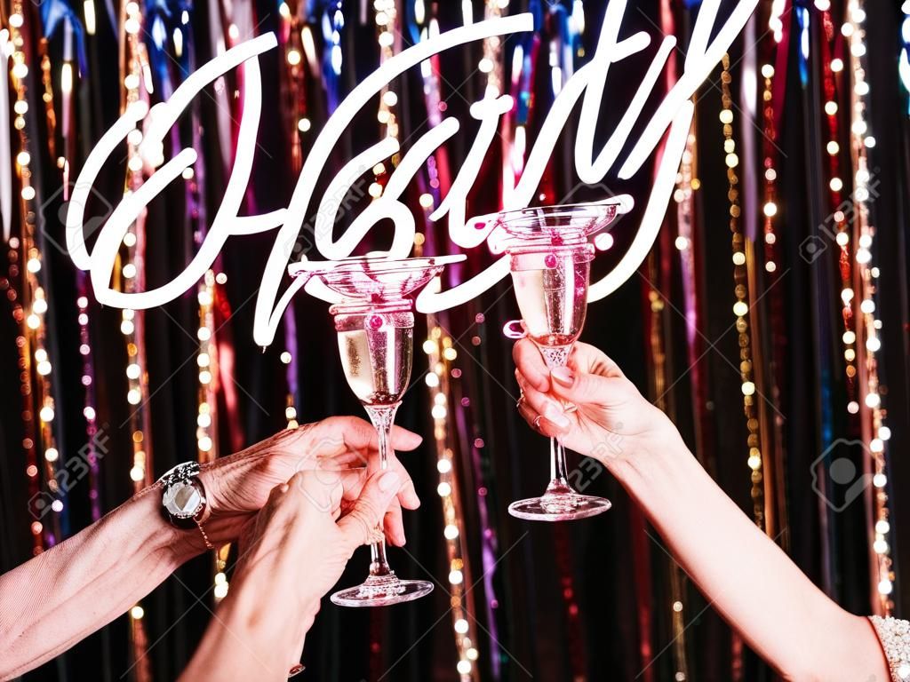 two hands of mature women drinking sparkling wine at the party. Holidays, life event, celebration