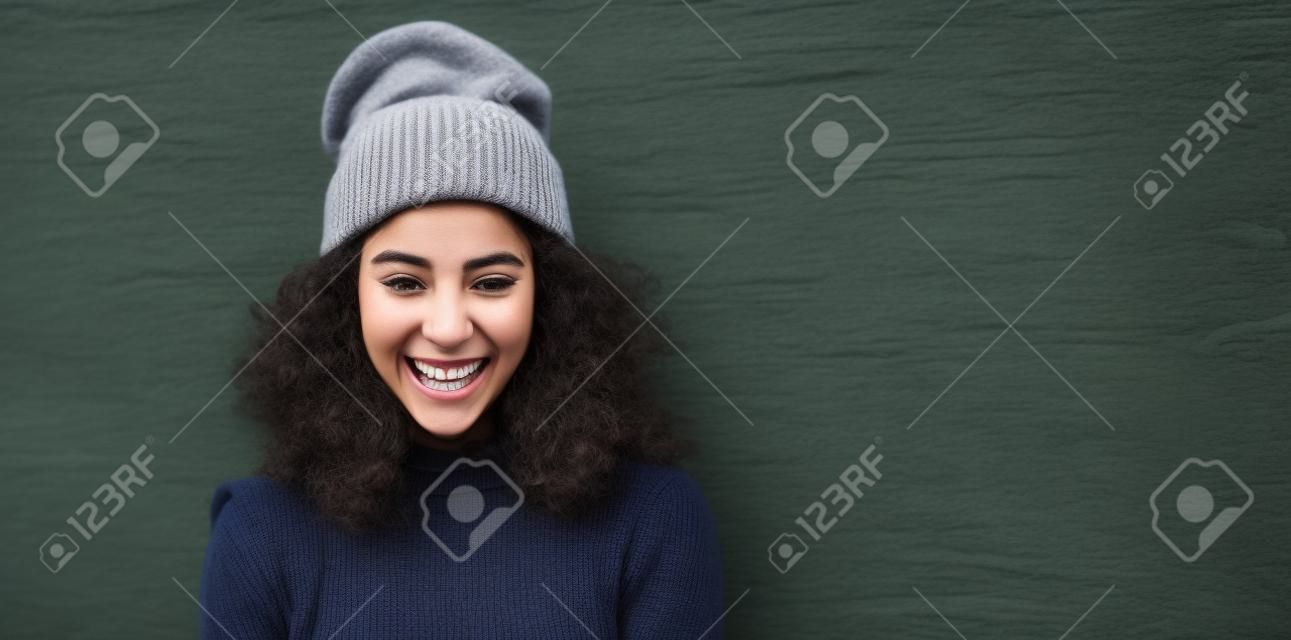 Śmiejąca się młoda dorosła kobieta z Ameryki Łacińskiej w czapce z dzianiny w miejskim stylu