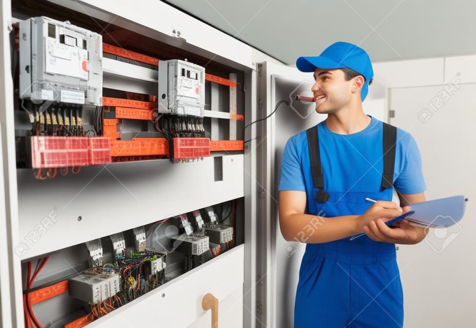 年輕的成年電工製造商的工程師檢查電氣櫃設備，配電保險絲盒