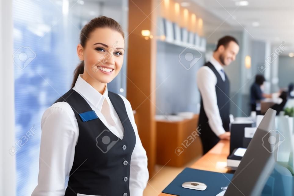 快樂的女接待員工人站在酒店櫃檯