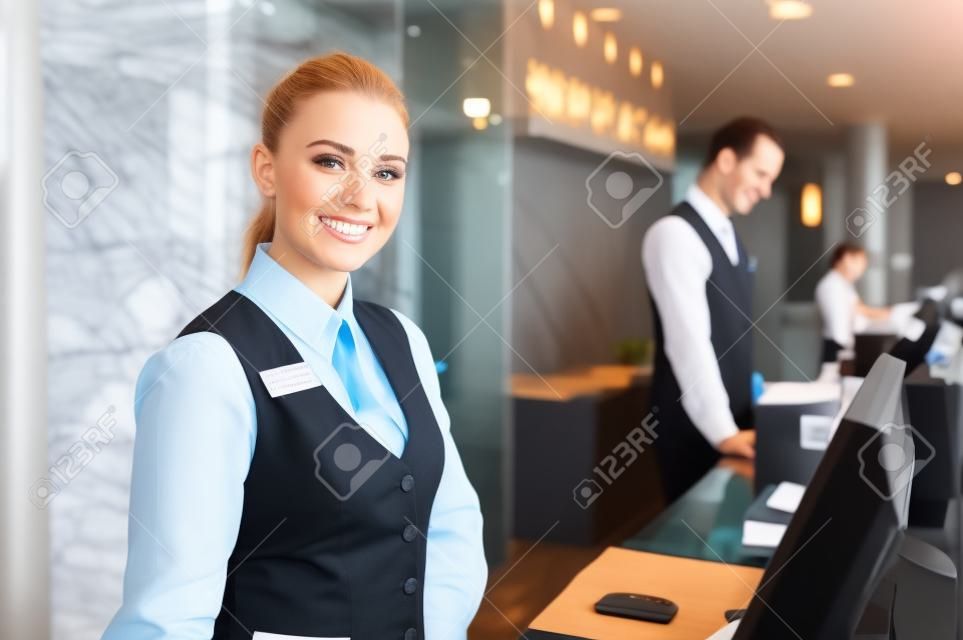 ホテルのカウンターに立っている幸せな女性受付ワーカー