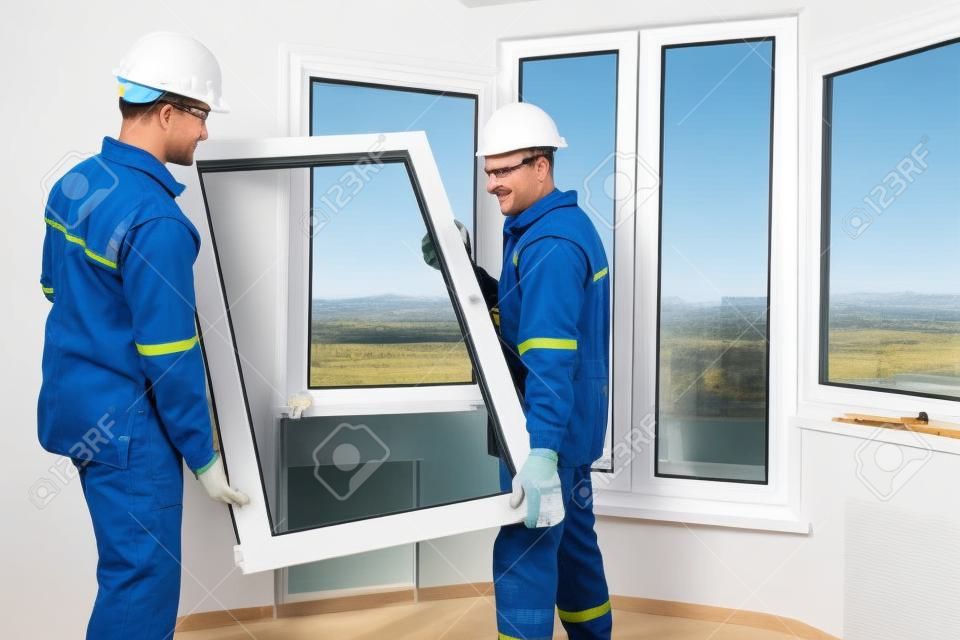 dois trabalhadores da instalação de janelas que instalam o painel dobro-vidro