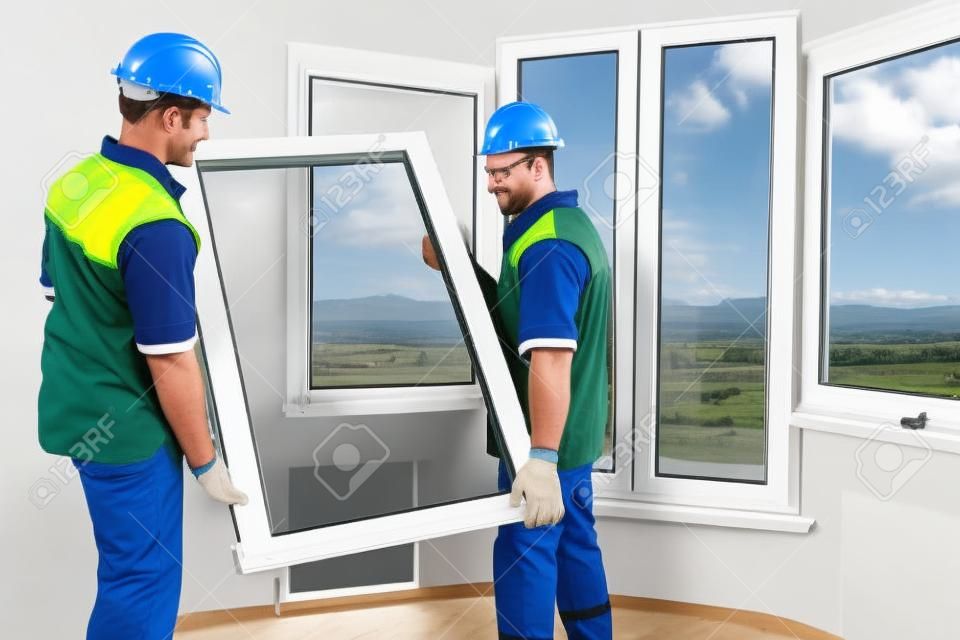 dois trabalhadores da instalação de janelas que instalam o painel dobro-vidro