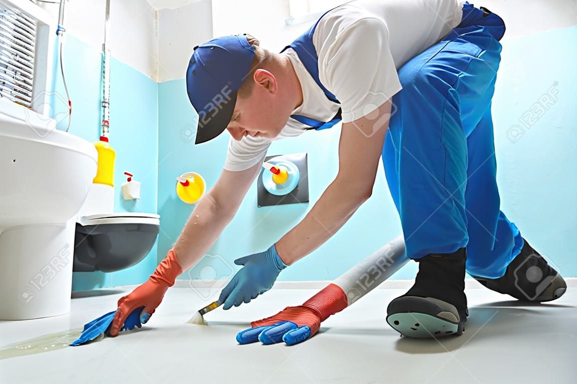 Impermeabilizzazione del pavimento in bagno. Lavoratore che aggiunge un rivestimento protettivo resistente all'acqua