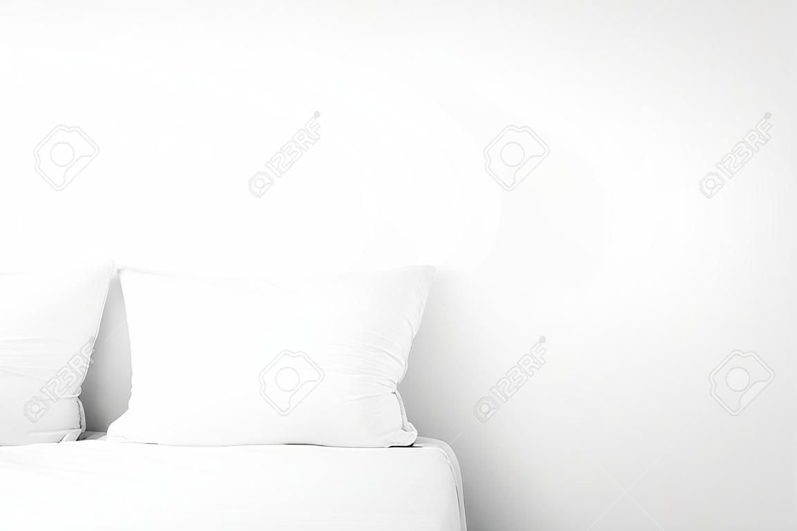 Soft pillows on bed near white wall