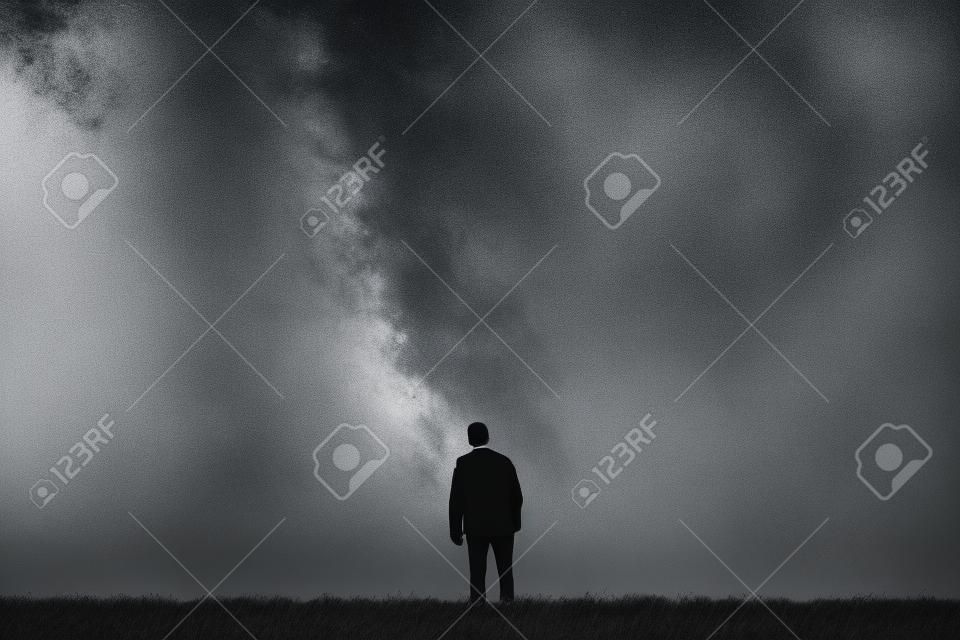Uomo solo si erge all'orizzonte. fotografia in bianco e nero di un uomo che guarda al cielo.