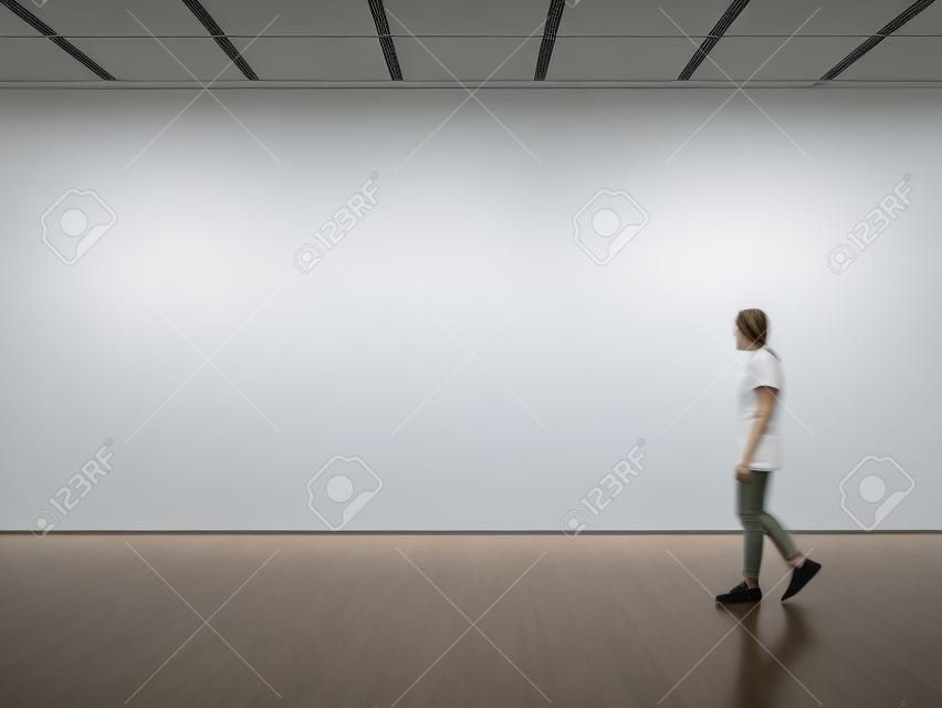 Photo of girl in modern gallery looking at the blank canvas. Horizontal