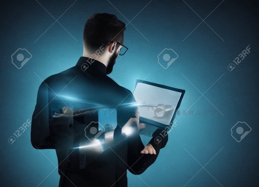 Double exposure  young bearded businessman wearing black shirt and holding contemporary notebook hands. Isolated white, night city background.