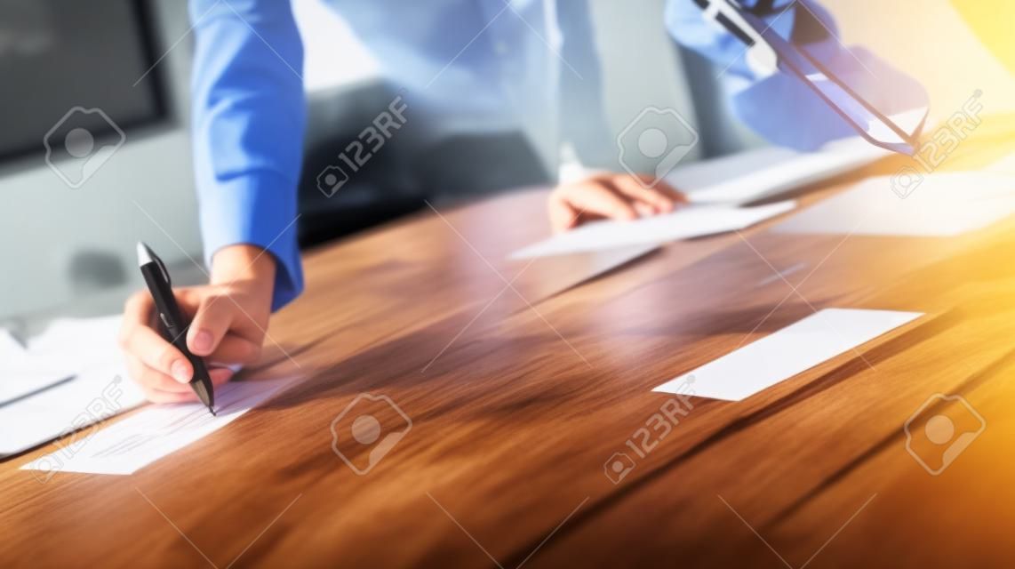 Closeup view of teamwork concept.Young business team working with new startup project.Smartphone on wooden table,documents and marketing reports.Blurred background,visual effect,flare.Horizontal