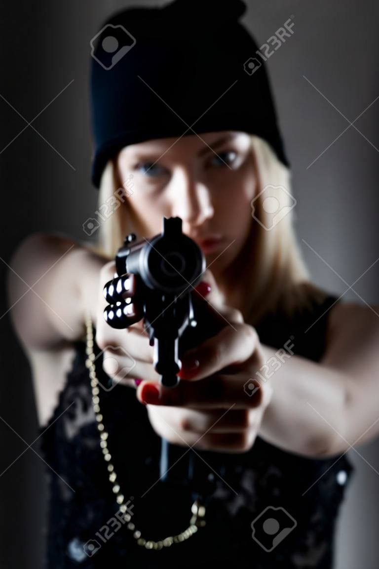 Portrait eines jungen Mädchens mit einer Pistole. Hooligan in einer dunklen Kappe zielt auf den Feind. Sharpshooter Pistol