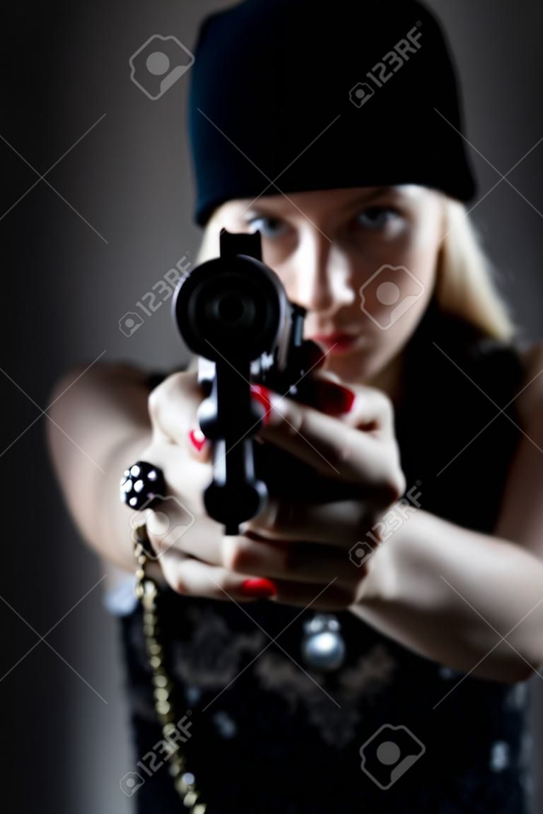 Portrait eines jungen Mädchens mit einer Pistole. Hooligan in einer dunklen Kappe zielt auf den Feind. Sharpshooter Pistol