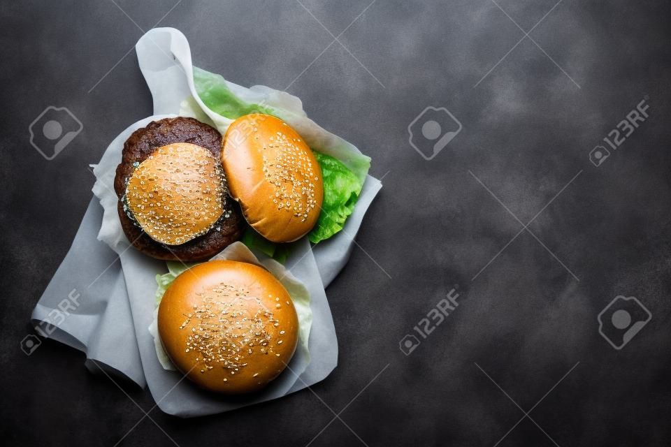 Dwa domowe, smaczne burgery z dużą wołowiną, serem, pomidorem, bekonem i sałatą. widok z góry na płasko z miejscem na kopię