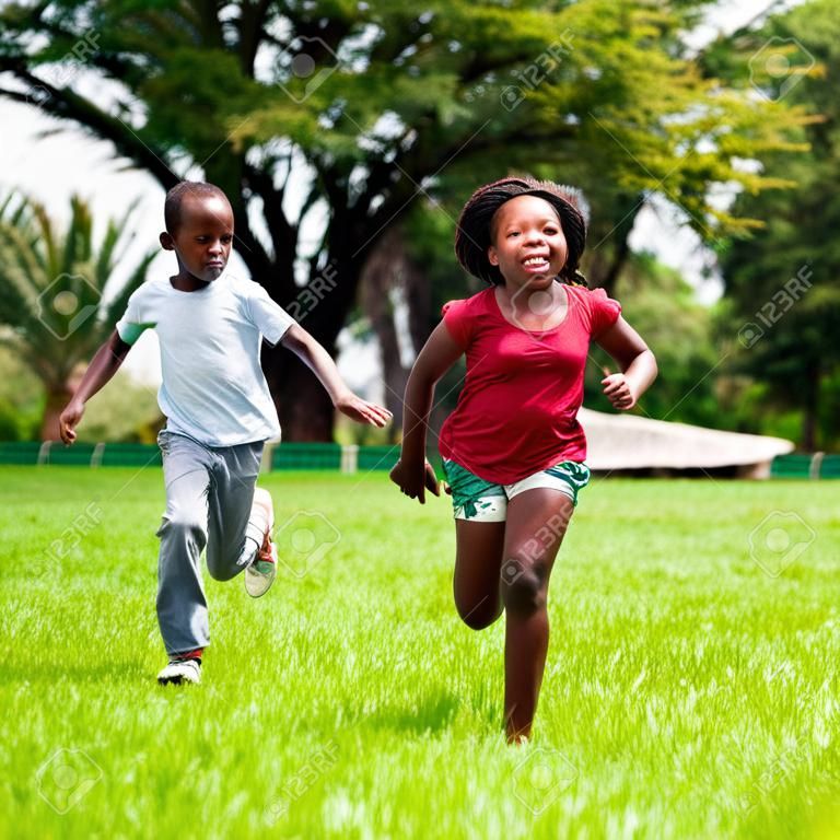 Action portrait of African kids playing and running together in park.