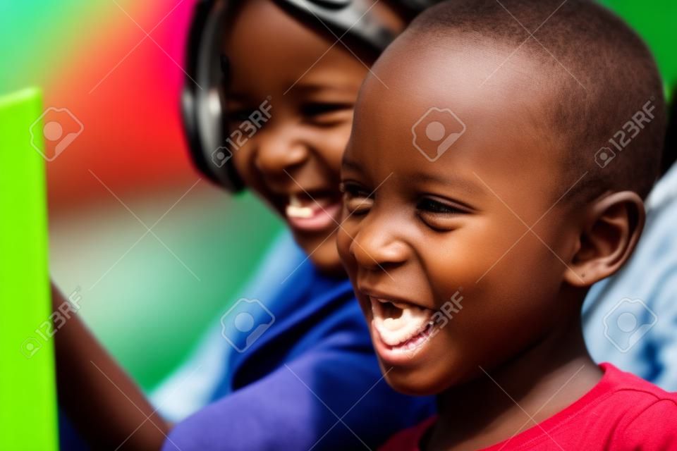 Bliska strzał z twarzy afrykańskich dzieci śmieje filmu sceny na cyfrowym tablecie zewnątrz.