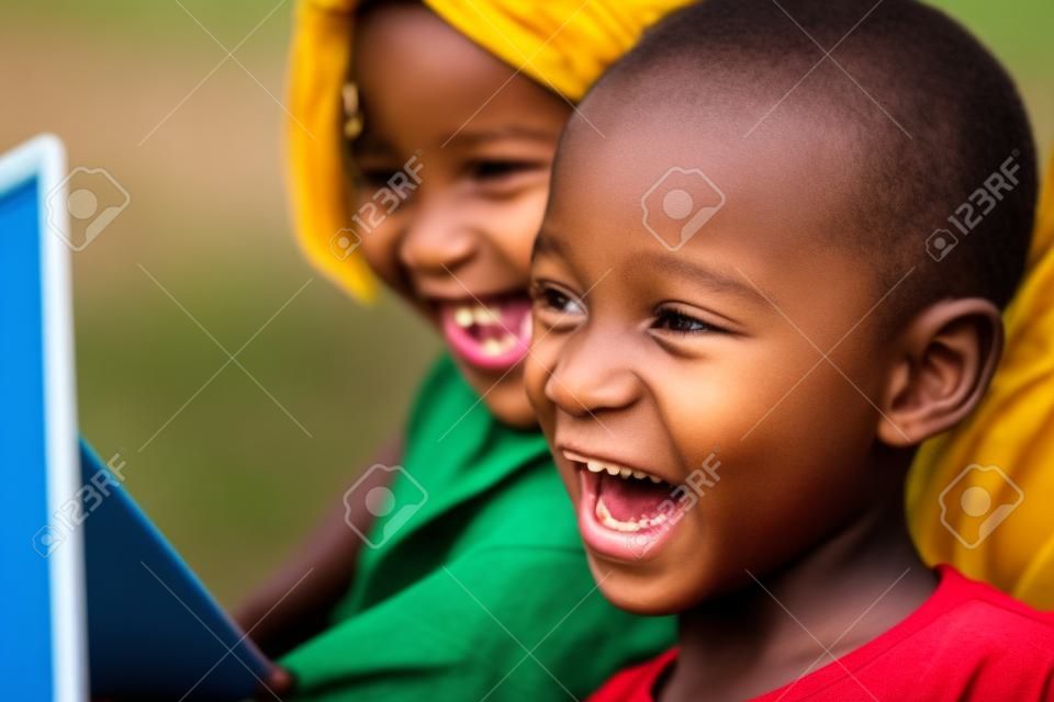 Close up visage tir d'enfants africains de rire de scène de film sur tablette numérique extérieur.