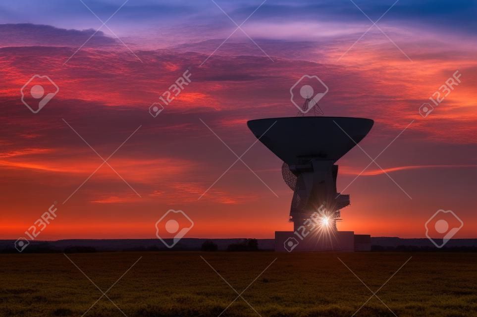 Antena de radar espacial. Prato de satélite ao pôr do sol com céu nublado.