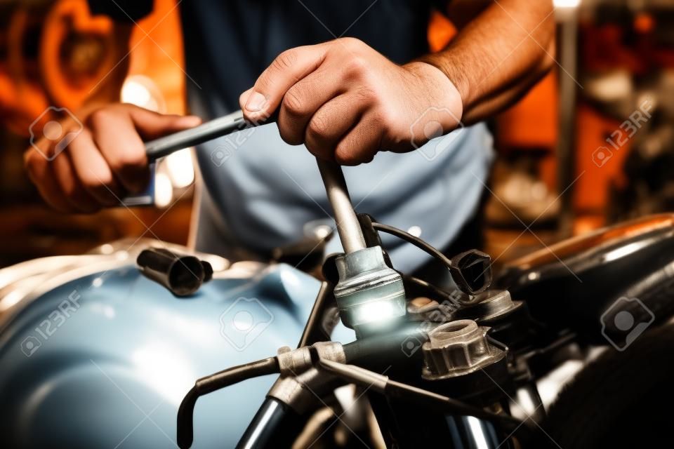 Mechanic using a wrench and socket on motorcycle in garage .maintenance,repair motorcycle concept .selective focus