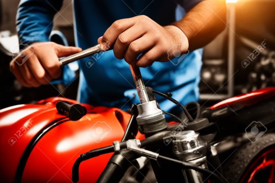 Mechanic using a wrench and socket on motorcycle in garage .maintenance,repair motorcycle concept .selective focus