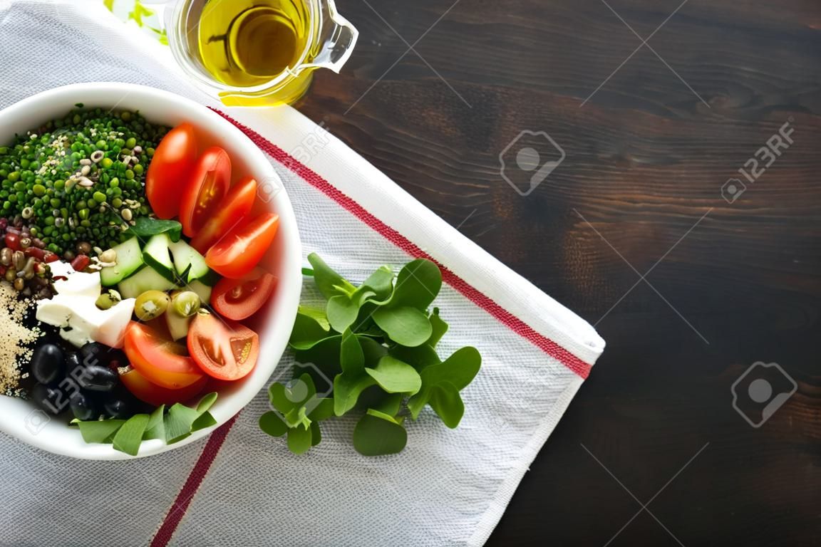 Wegetariańska wegańska miska sałatkowa lub miska buddy z pomidorem, ogórkiem, serem mozzarella, komosą ryżową, oliwkami i mikrogreenami. koncepcja zdrowej i zrównoważonej żywności na starym drewnianym ciemnym tle widok z góry miejsce na kopię