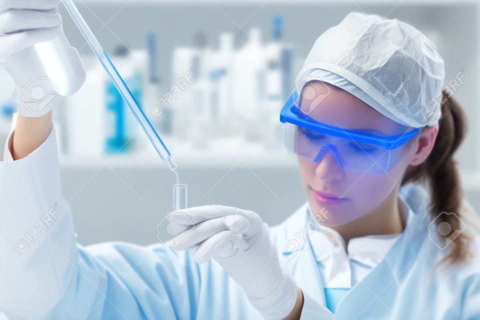 Lebenswissenschaftler erforscht im Labor. Focused weiblichen Life Science Berufs Pipettieren Lösung in die Glasküvette. Objektiv Fokus auf die Augen Forschers. Healthcare und Biotechnologie-Konzept.