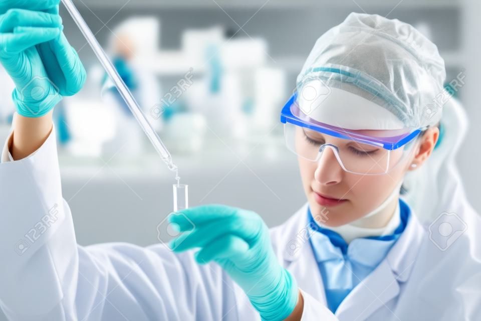 生命科学家在实验室集中研究女性生命科学专业的移液溶液注入玻璃比色皿镜头聚焦者的眼睛保健和生物技术的概念