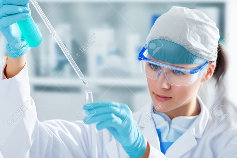 生命科学家在实验室集中研究女性生命科学专业的移液溶液注入玻璃比色皿镜头聚焦者的眼睛保健和生物技术的概念