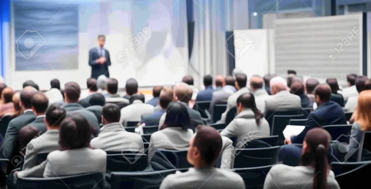 Sprecher, der einen Vortrag im Konferenzsaal bei einer Geschäftsveranstaltung hält. Rückansicht von nicht erkennbaren Personen im Publikum im Konferenzsaal. Geschäfts- und Unternehmertumskonzept.
