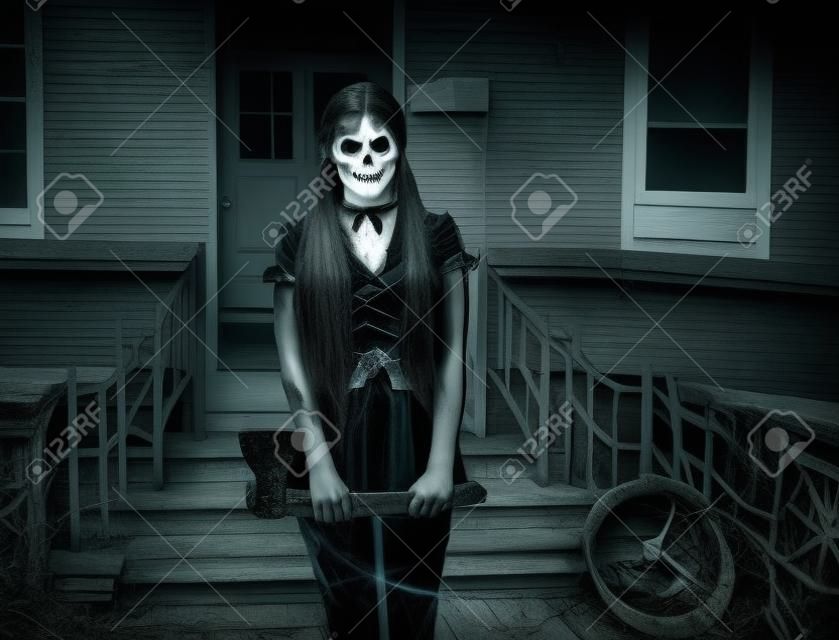 Halloween horror. Scary woman ghost with ax on porch of house