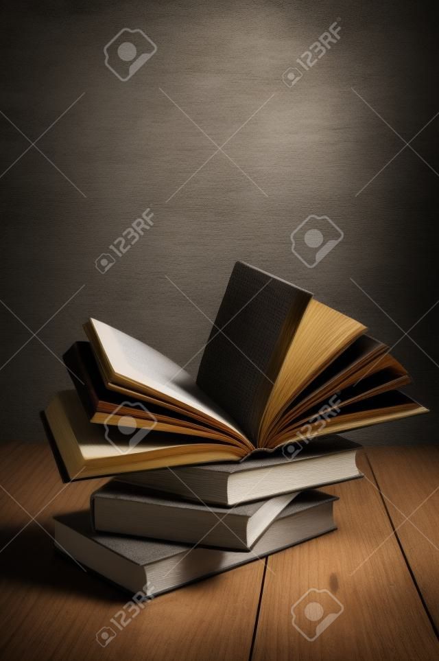 stack of books on a wooden table and on gray concrete wall background