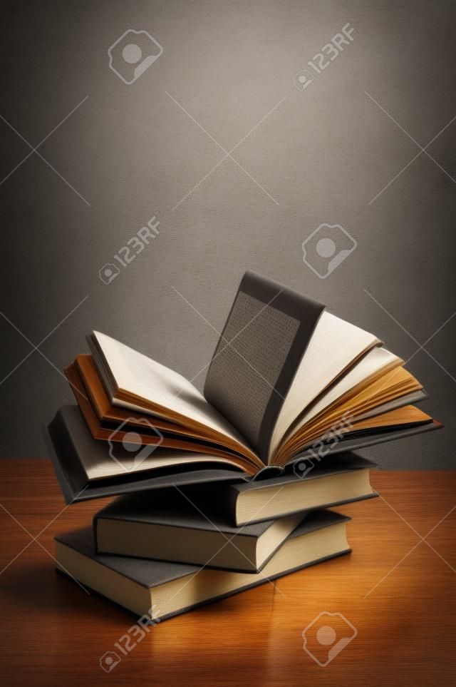 stack of books on a wooden table and on gray concrete wall background
