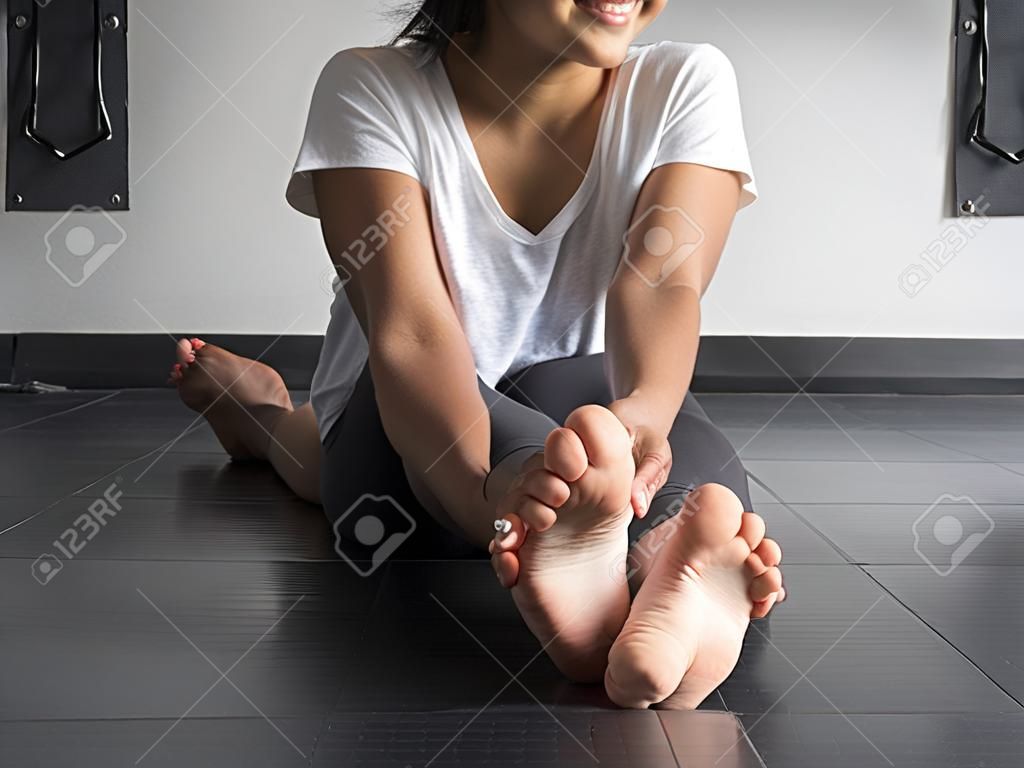 Smiling dancer warming up her feet with alternating pointing and flexing