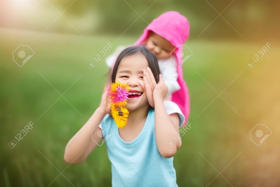 Fröhliches und verspieltes kleines Mädchen, das die Augen der Mutter von Hand bedeckt und eine Blumenüberraschung vorbereitet