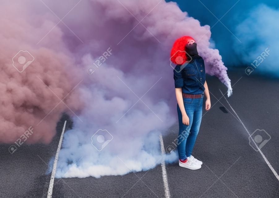 街の煙爆弾の近くに立っているスタイリッシュなティーンエイジャー