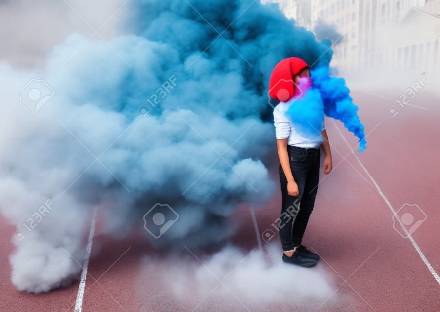 Stilvoller Teenager, der in der Stadt in der Nähe einer Rauchbombe steht