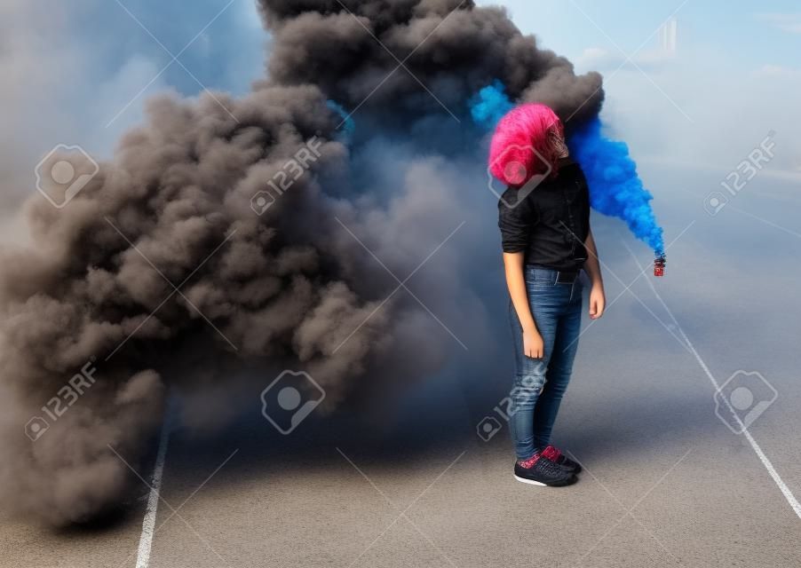 Adolescente elegante que está perto da bomba de fumaça na cidade
