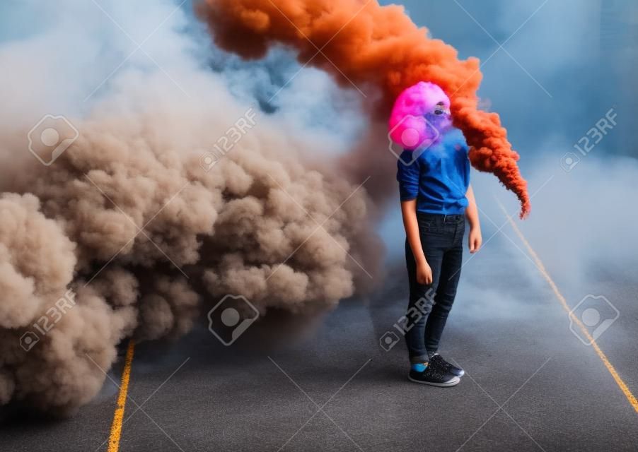 Stilvoller teenager, der in der stadt in der nähe einer rauchbombe steht
