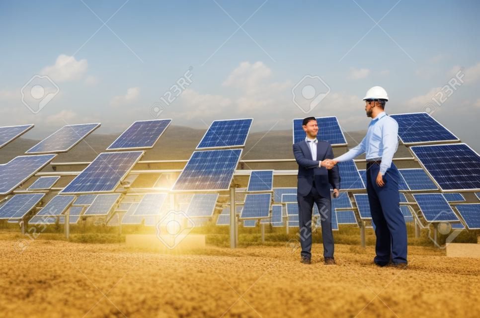 Supervisor e engenheiro apertando as mãos no campo de energia solar