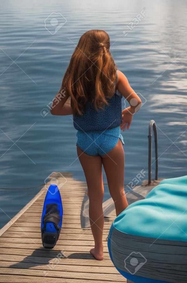 Rear view of a girl standing on a pier at the lakeside, Lake of The Woods, Keewatin, Ontario, Canada