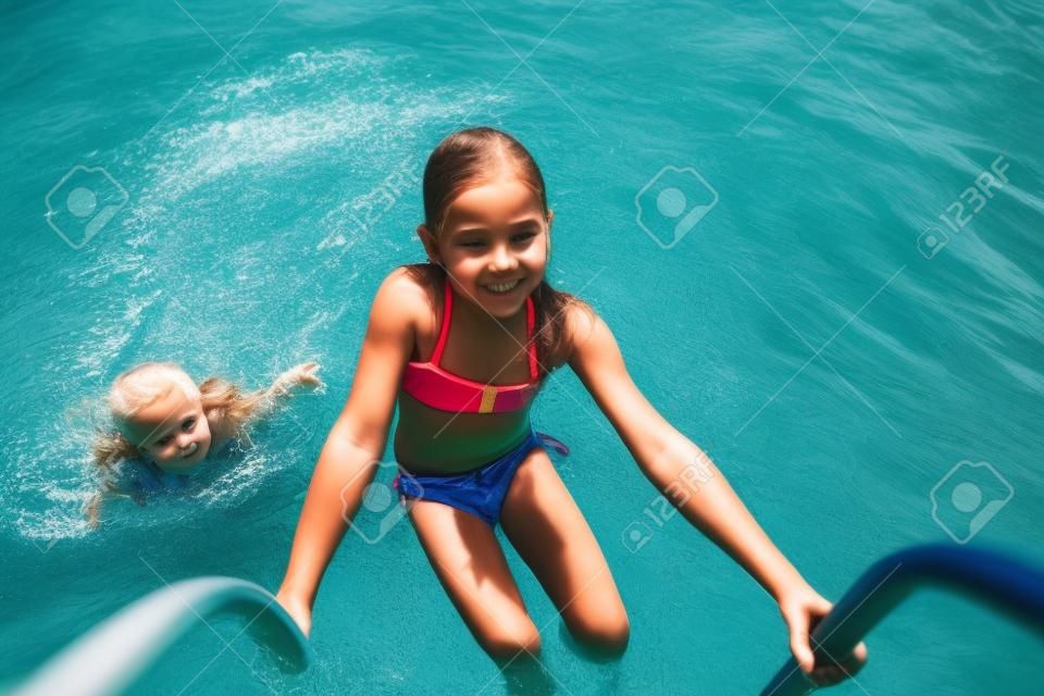 はしごを使用して水から抜け出す小さな女の子