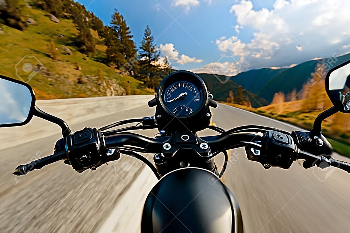Motorcycle driver riding in Alpine highway, handlebars view, Austria, central Europe.