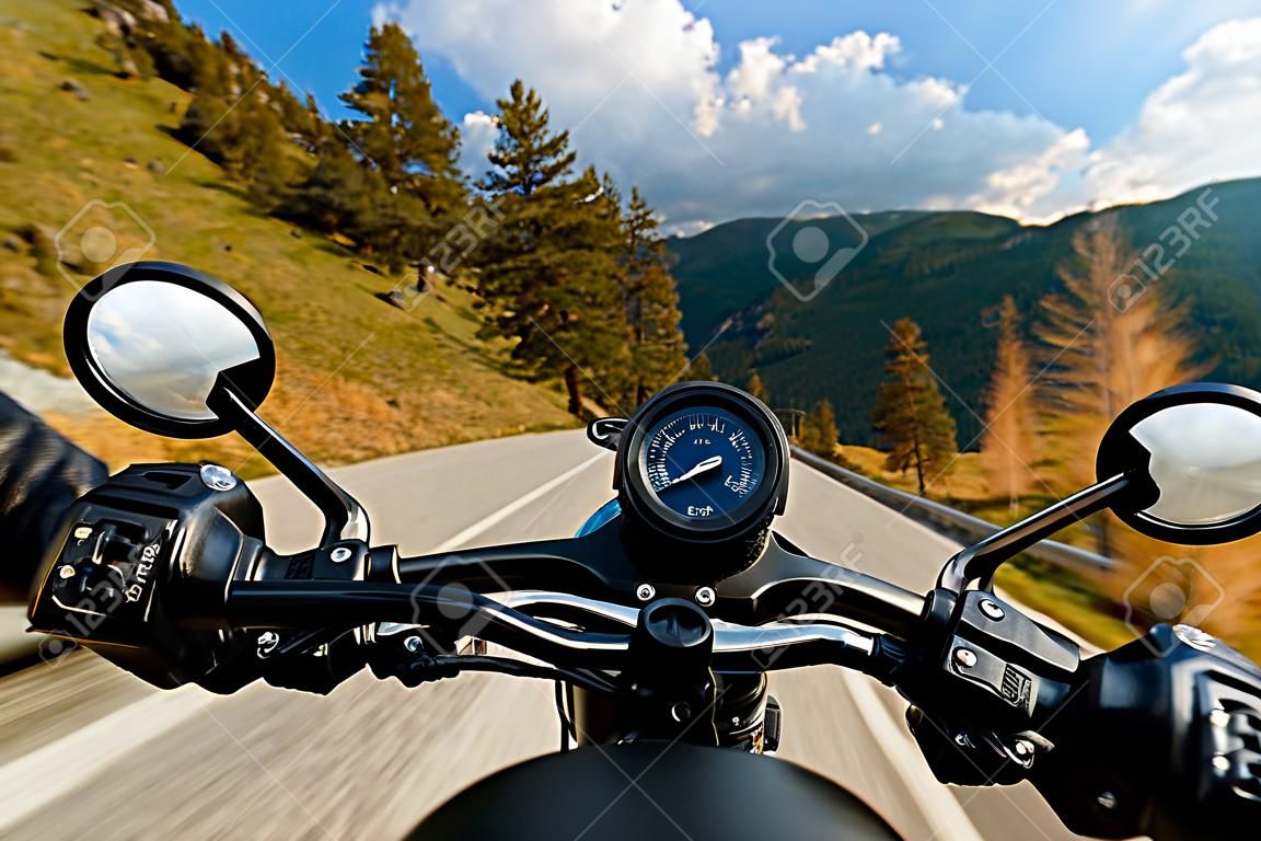 Motorcycle driver riding in Alpine highway, handlebars view, Austria, central Europe.