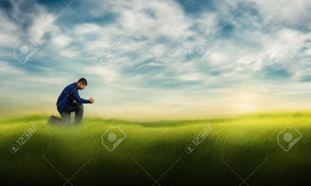 El hombre de rodillas en un campo para orar