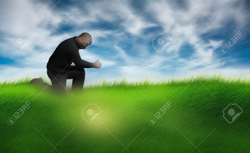 De mens die bidt in het grasveld