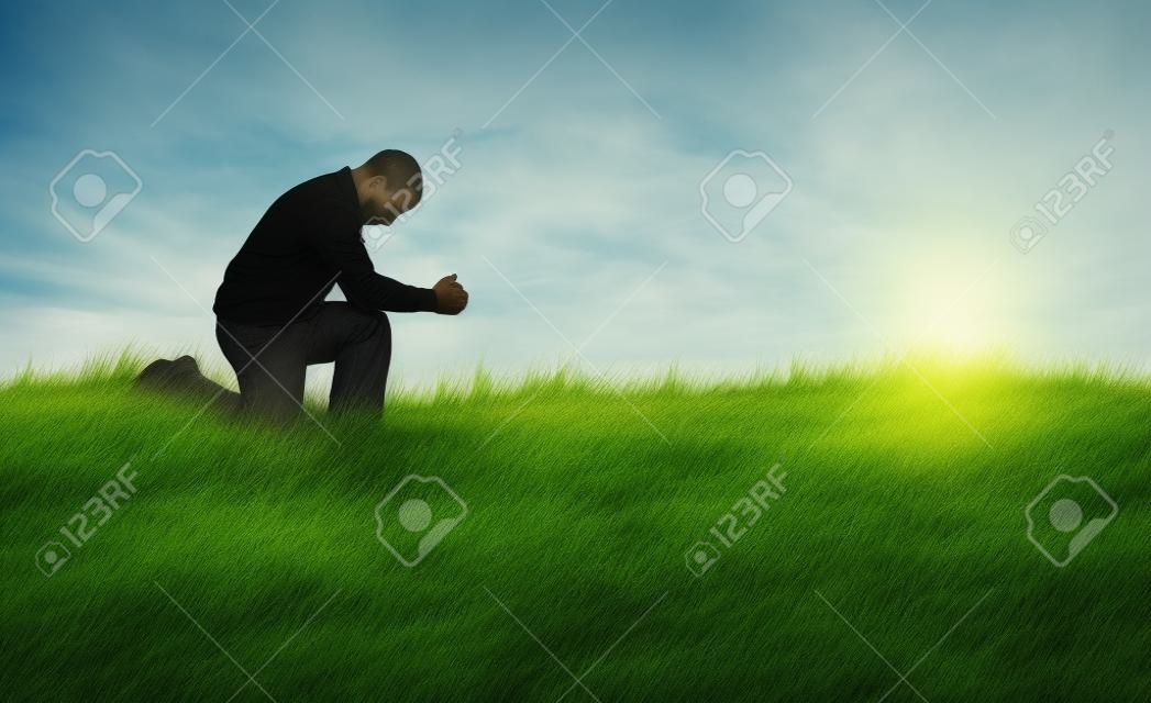 De mens die bidt in het grasveld