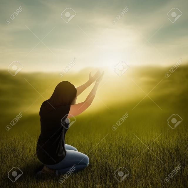 Una mujer de rodillas en adoración en un campo.